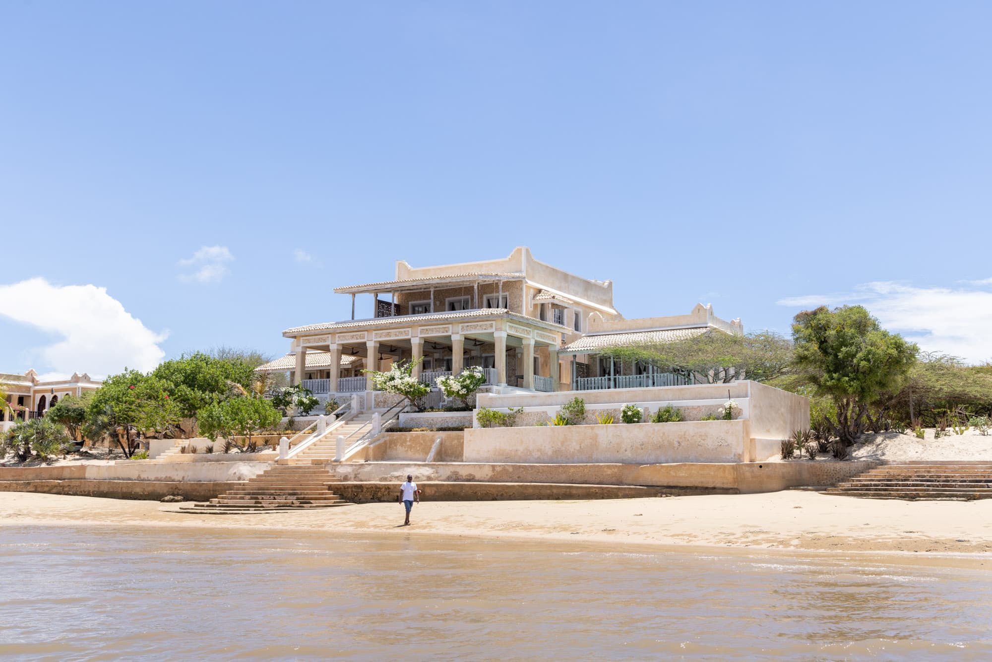 Amani House viewed from the beach, its full coral-stone facade facing the Indian Ocean, Manda Island